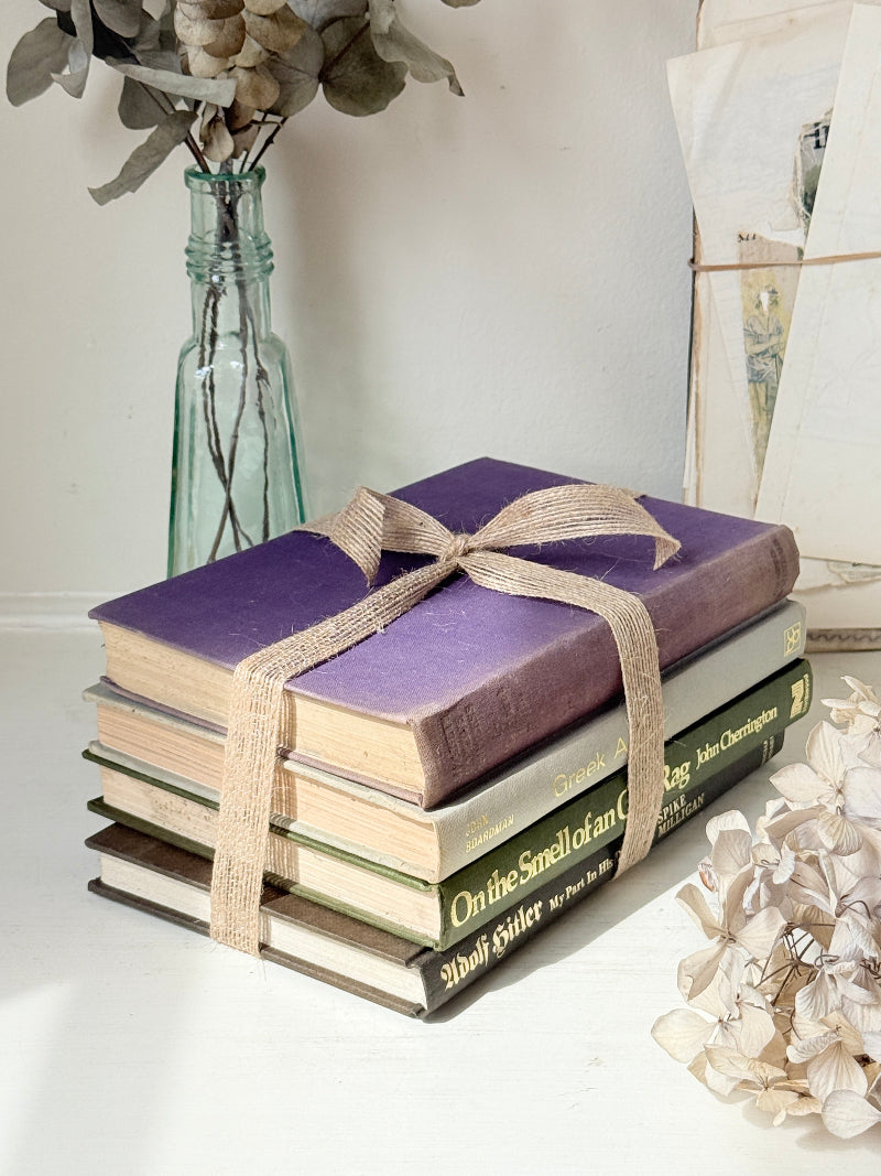 Bundle of vintage books with a heather purple cloth cover over green and cream spines tied with natural twine
