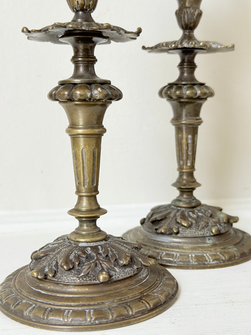 pair of antique brass candlesticks with turned detailing on white surface