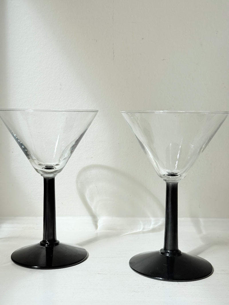 Set of six clear martini glasses with black stems, photographed on a white surface