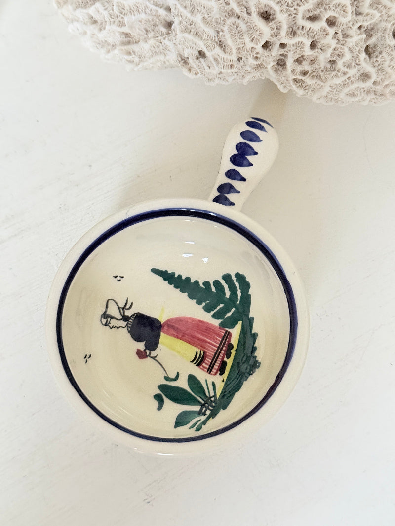 French Quimper faience handled olive bowl with Petit Breton figure and blue rim, photographed on a white surface