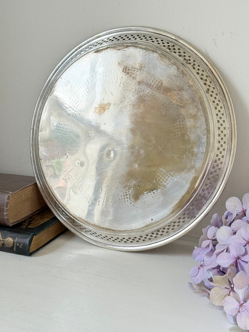 Vintage round silver plate tray with brass rim, pierced edge and etched central motif, photographed on white surface