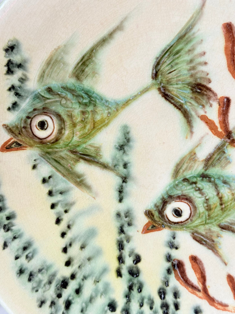 Puidgemont Spanish studio pottery plate with hand painted fish and coral design in green, turquoise, and terracotta tones, photographed on a white surface.