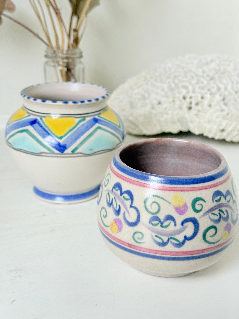 Pair of vintage studio pottery pots in blue green and pink glaze photographed on a white surface