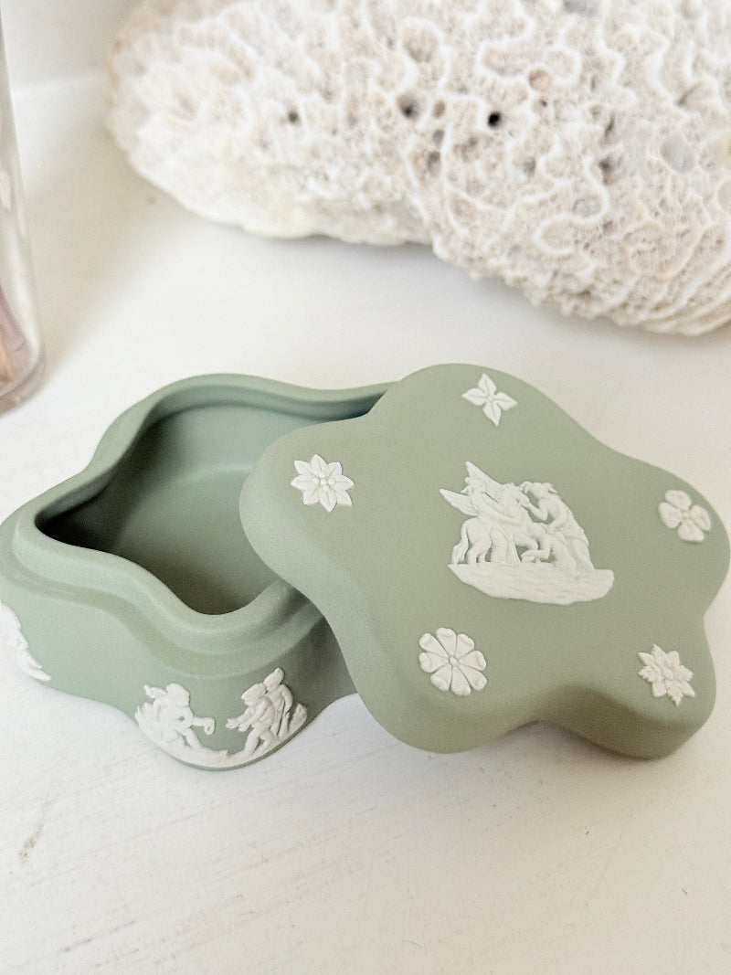 Vintage Wedgwood Jasperware sage green lidded trinket box in a quatrefoil shape, decorated with white neoclassical cherubs and florets, styled with dried stems.