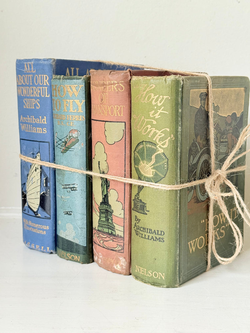 Vintage decorative book bundle in green, blue, and coral with printed lettering, tied with twine, photographed on a white surface