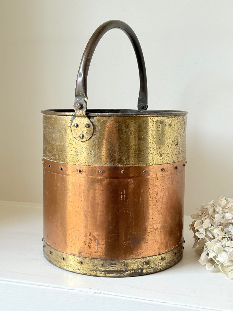 Vintage copper and brass metal bin with handle, photographed on a white surface.