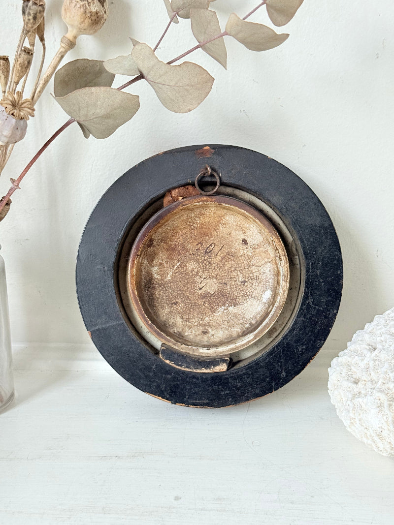 Antique Prattware framed ceramic lid with rural family scene photographed on a white surface.