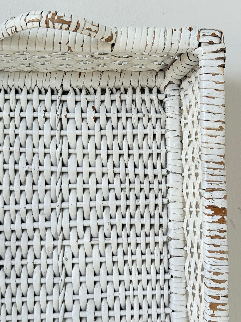 Vintage white painted wicker tray with woven handles photographed on a white surface