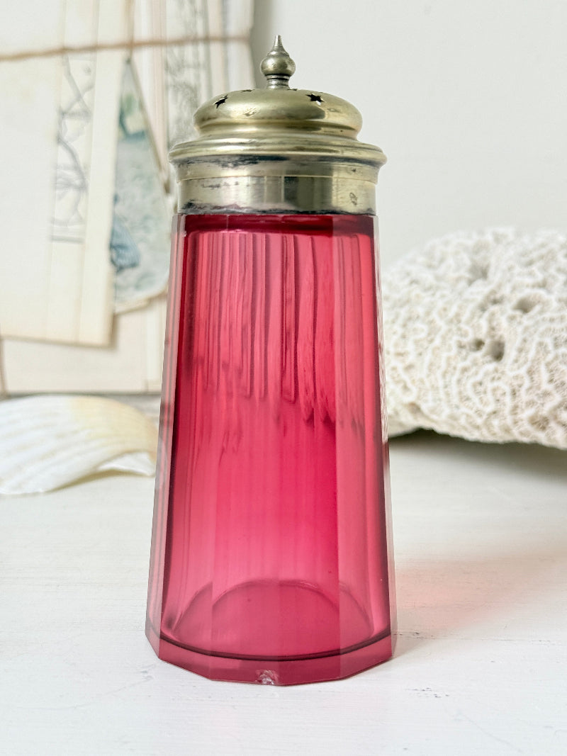 Antique cranberry glass sugar shaker with ribbed optic body, pierced metal top, star holes and deep pink glass