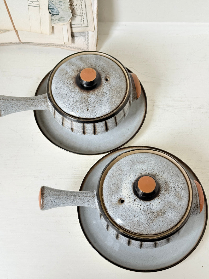 Denby Studio pair of lidded soup bowls with stands in grey and rust photographed on a white surface