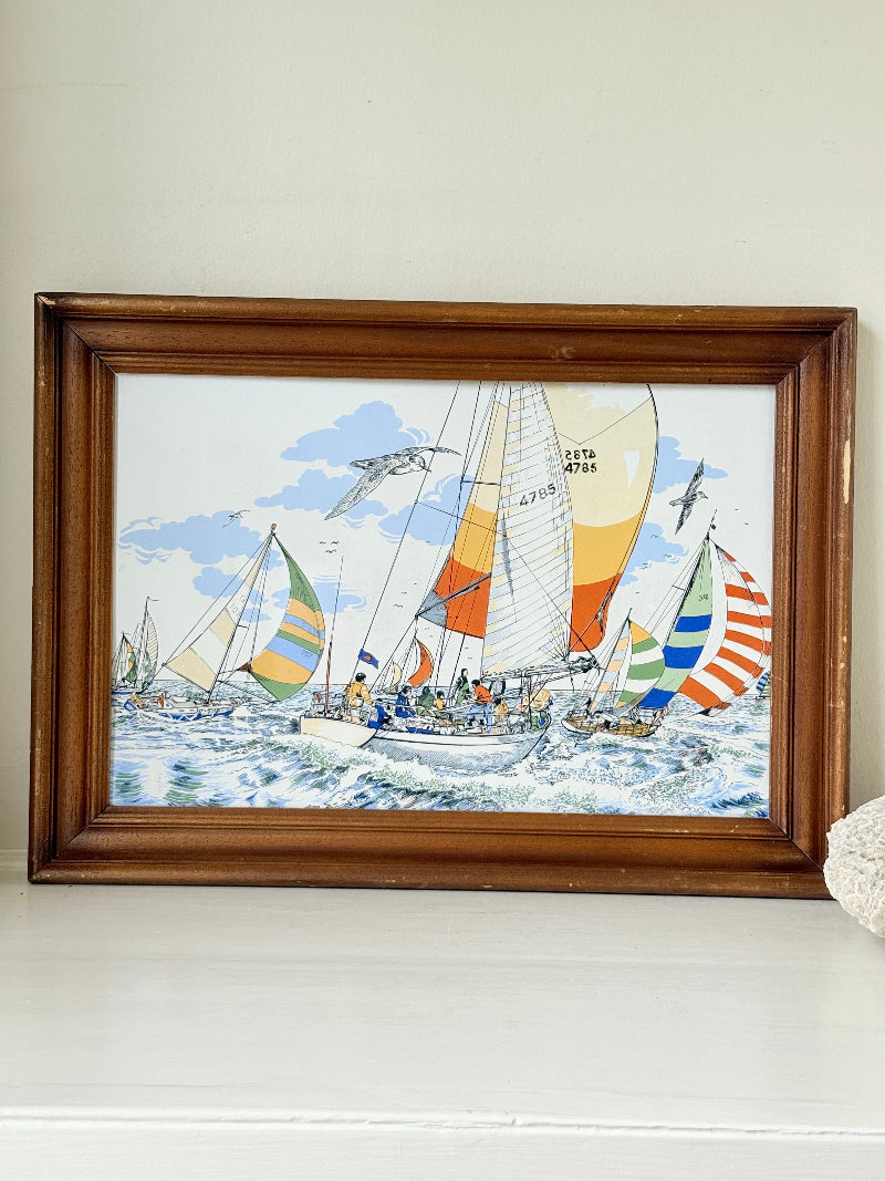 Vintage enamel artwork of sailing yachts with colourful striped sails in a regatta, framed in wood, photographed on white surface.