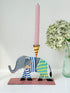 Hand painted metal elephant candlestick in circus-style decoration with colourful patterns, photographed on a white surface