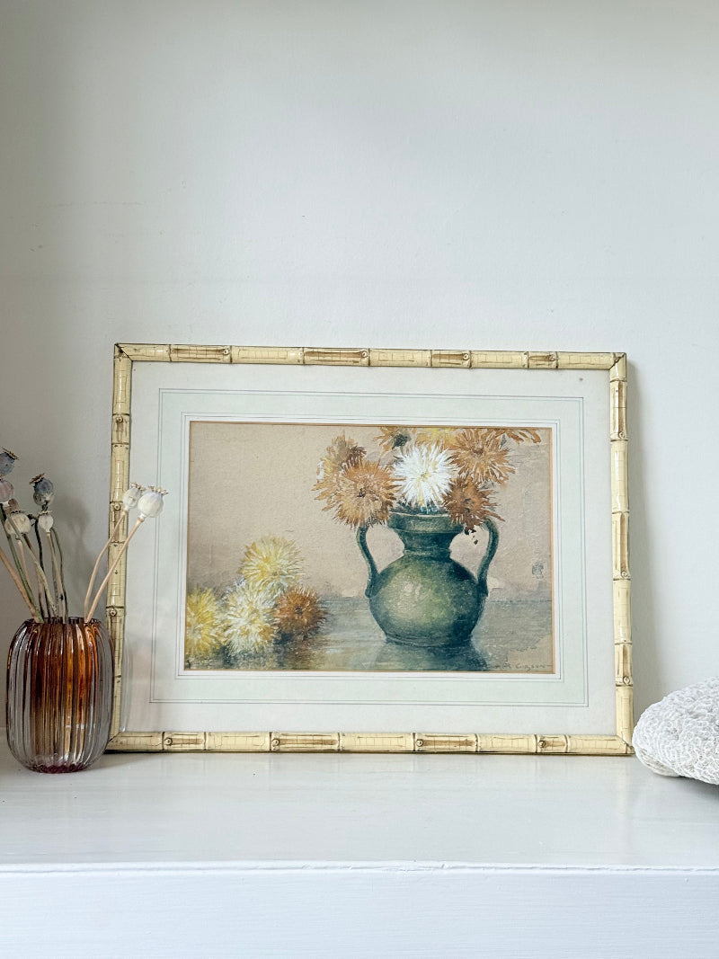 Vintage watercolour of chrysanthemums in green vase, under glass, in cream faux bamboo frame, photographed on white surface.