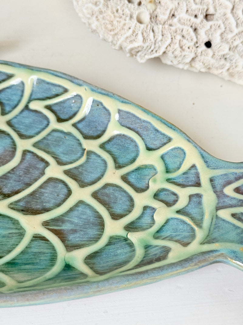 Barbados studio pottery fish platter in turquoise and sea green glaze photographed on a white surface