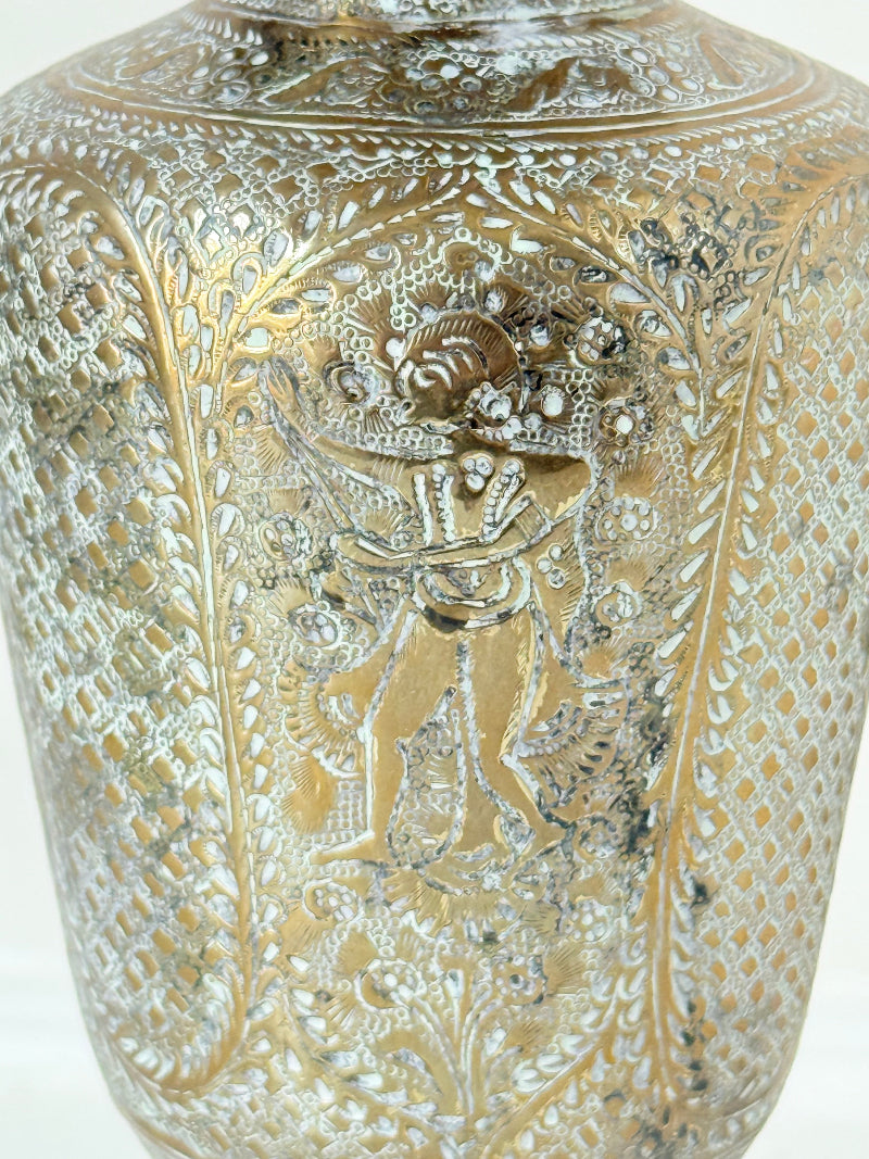 Indian Benares brass lidded vase with engraved figures and pedestal base, photographed on a white surface