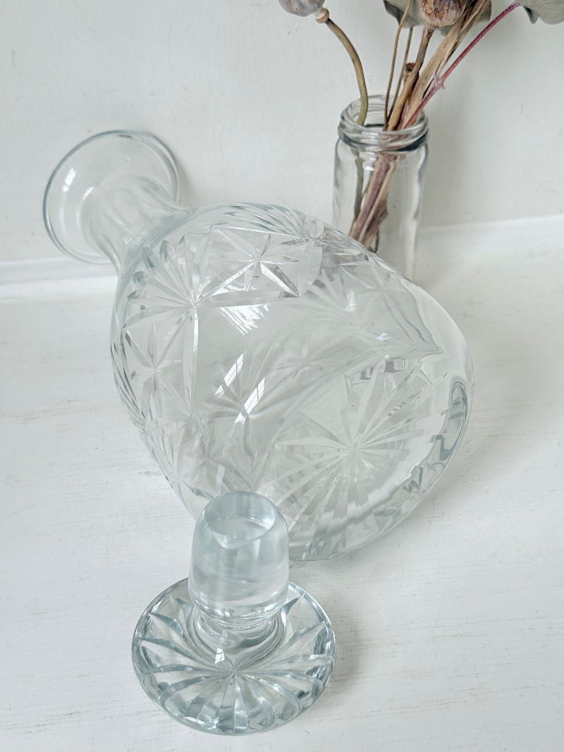 Vintage crystal decanter with faceted stopper and cut glass starburst design, photographed on a white surface