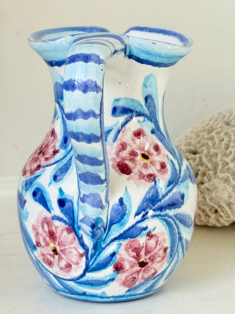 Portuguese studio pottery jug with blue and pink hand painted floral design, photographed on a white surface