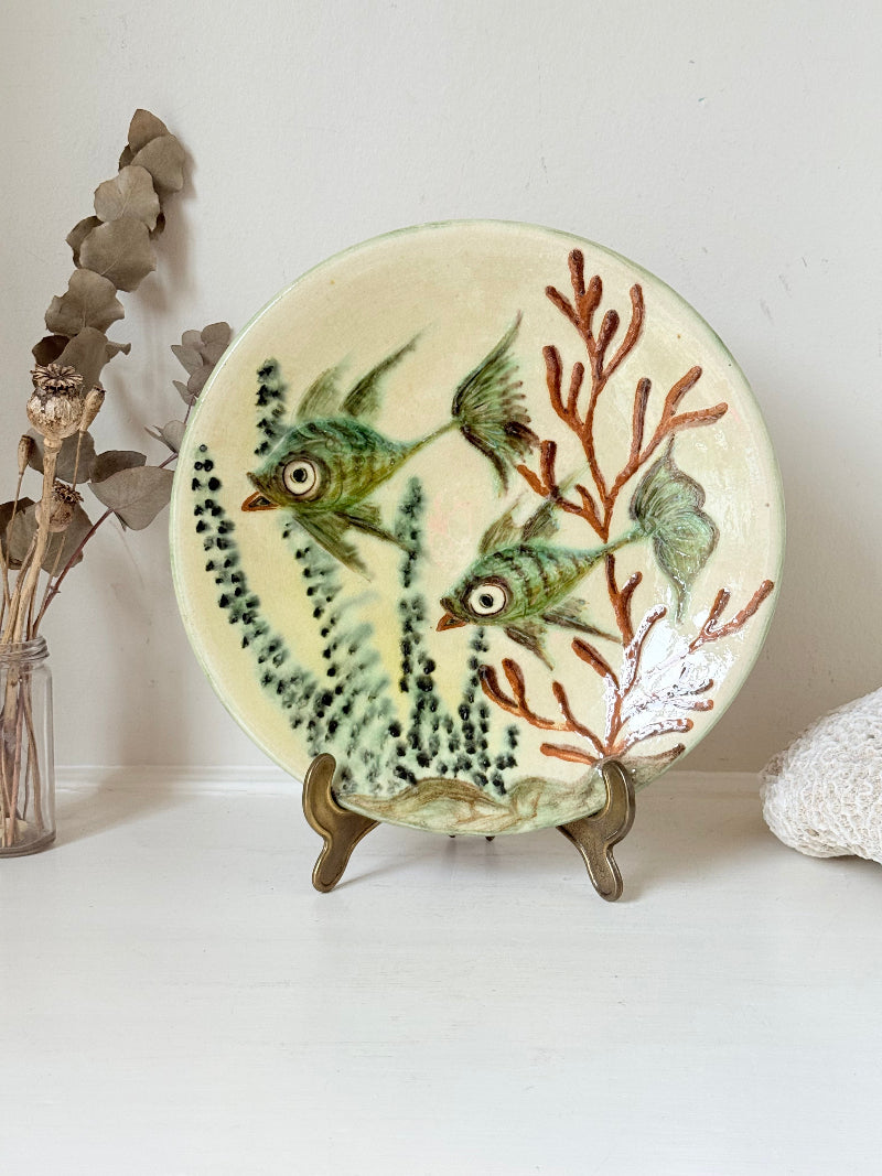 Puidgemont Spanish studio pottery plate with hand painted fish and coral design in green, turquoise, and terracotta tones, photographed on a white surface.