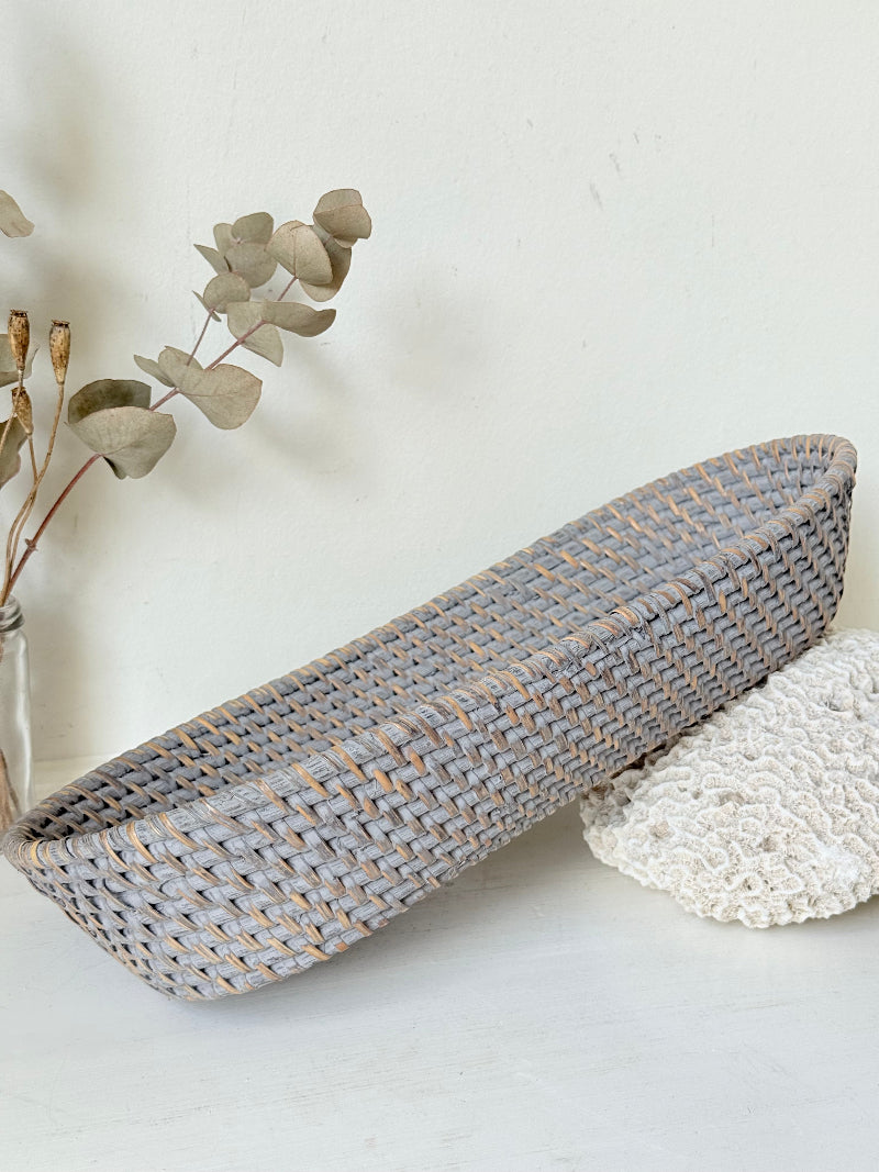Vintage grey woven bread basket with oval shape and raised rim, photographed on white surface.