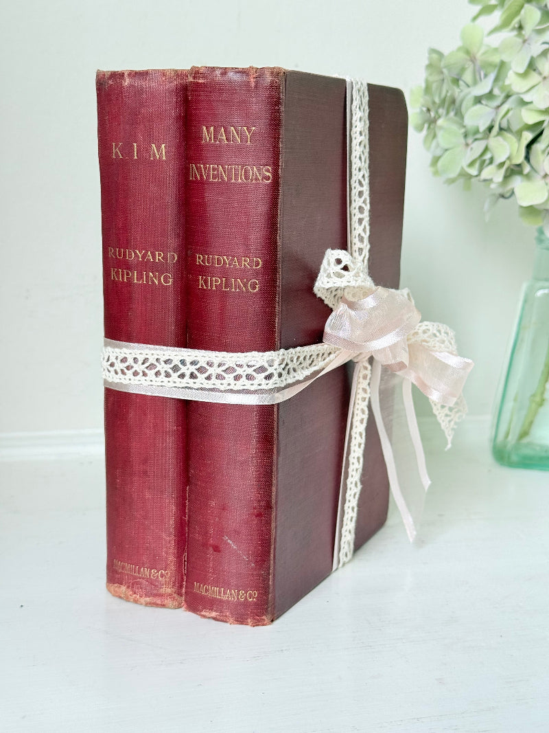 Pair of vintage Rudyard Kipling books in red cloth bindings with gilt lettering, styled as a decorative bundle, photographed on a white surface
