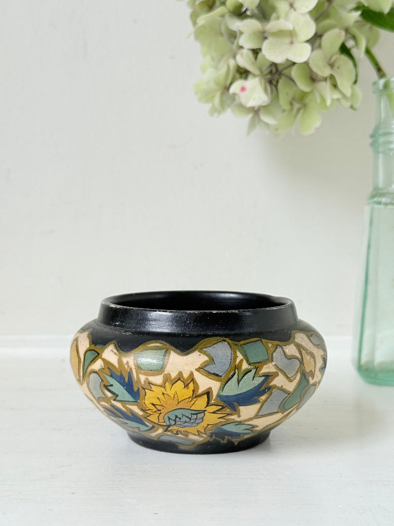 Brentleigh Ware Art Deco pottery jar with hand painted floral decoration on a black ground, photographed on a white surface