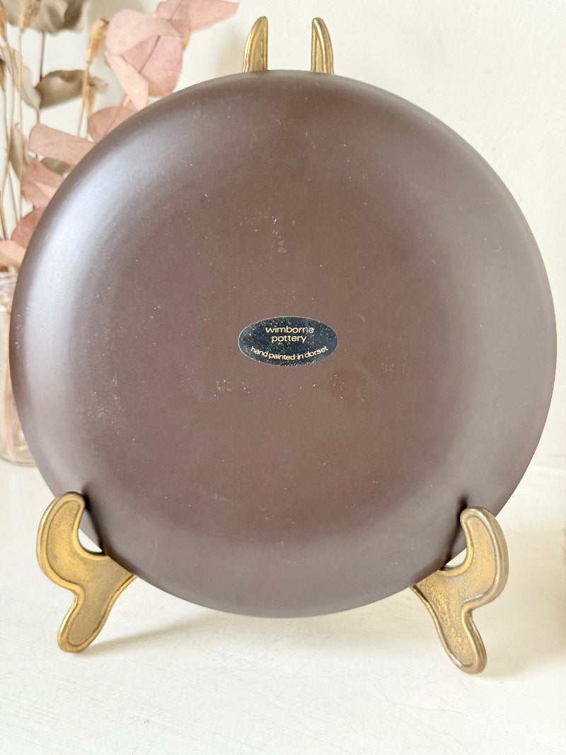 Vintage plate with hand painted brown donkey illustration and dark rim, photographed on a white surface