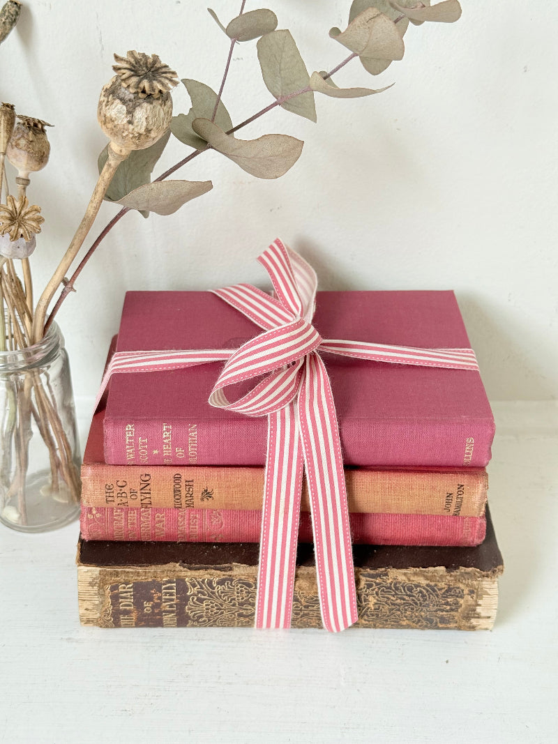 Vintage autumn colours decorative book bundle with pink ribbon, photographed on a white surface
