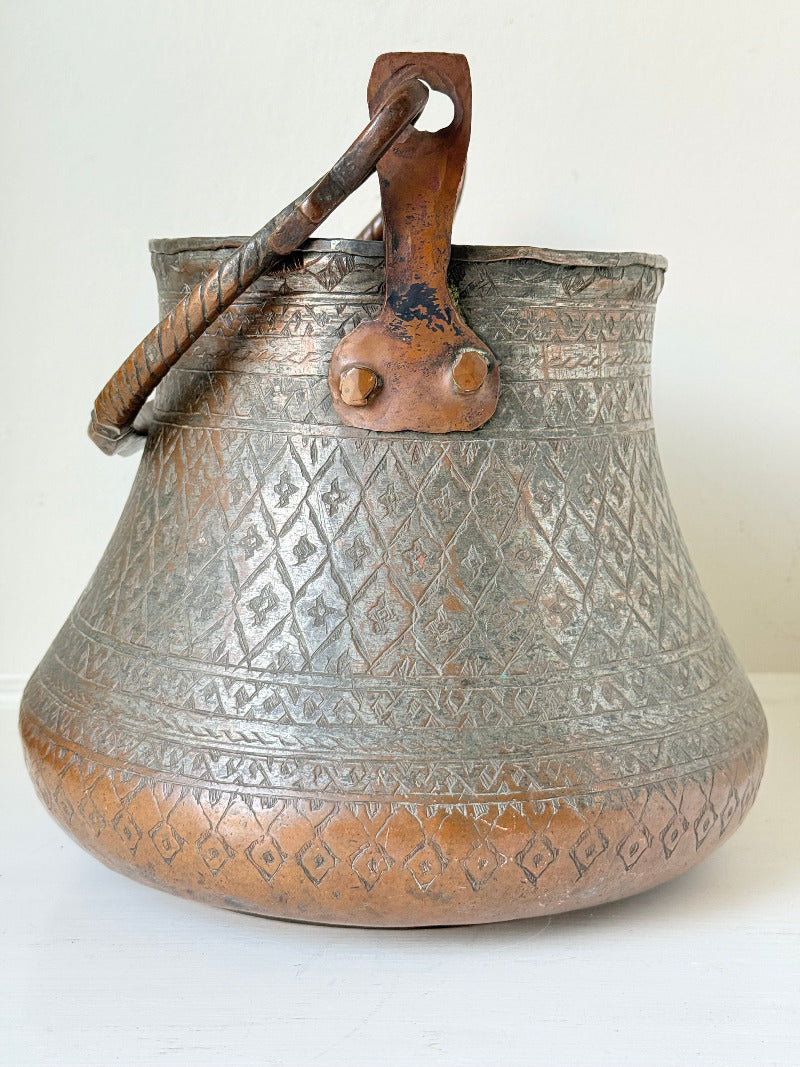 antique Middle Eastern water ewer with engraved diamond and foliate pattern and copper base, displayed on white surface