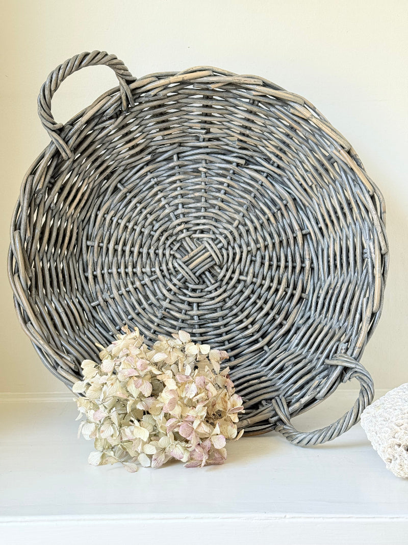 Large vintage woven basket with handles, photographed on a white surface