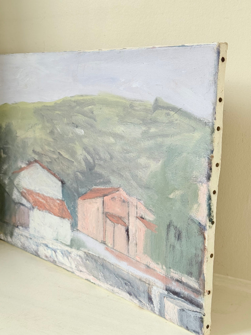 Unframed vintage oil painting of hillside cottages with terracotta roofs, green landscape, and textured brushwork, on white surface.