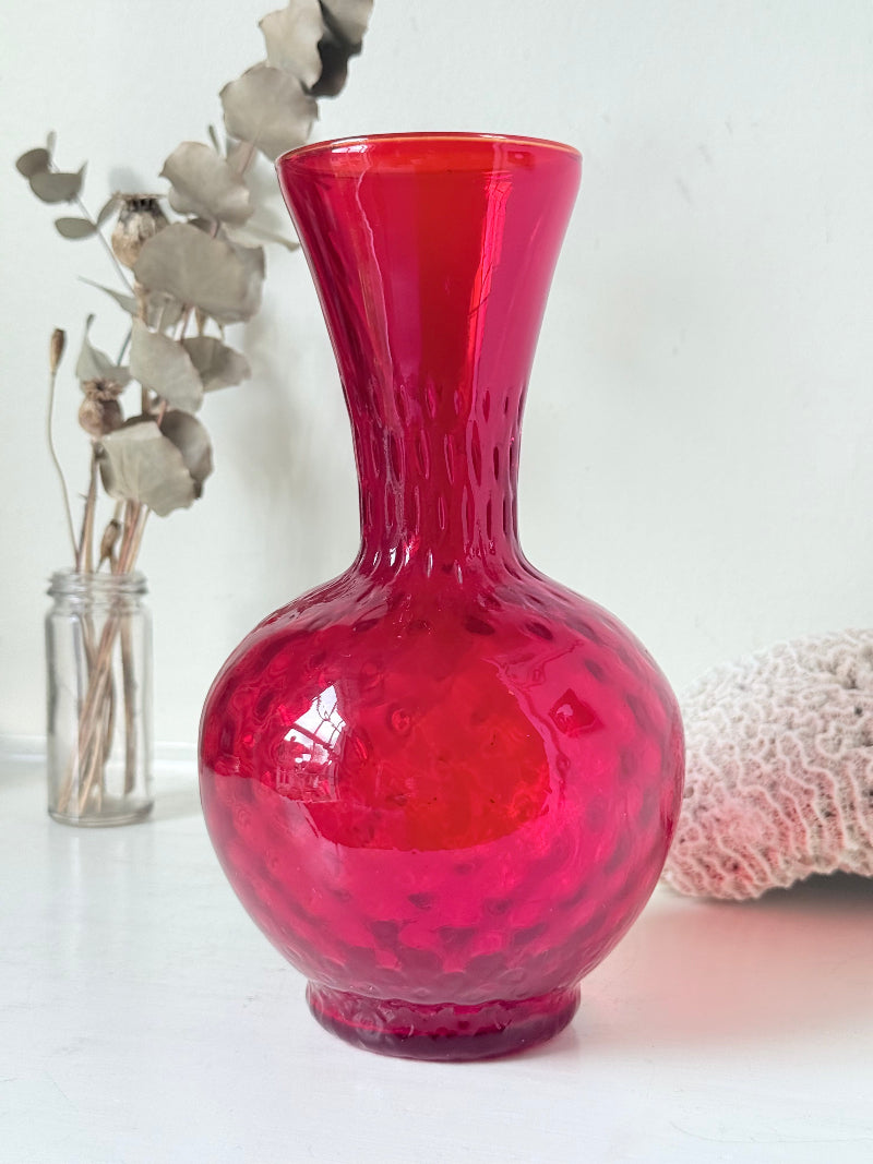 Italian red glass vase with strawberry textured surface, photographed on a white background.