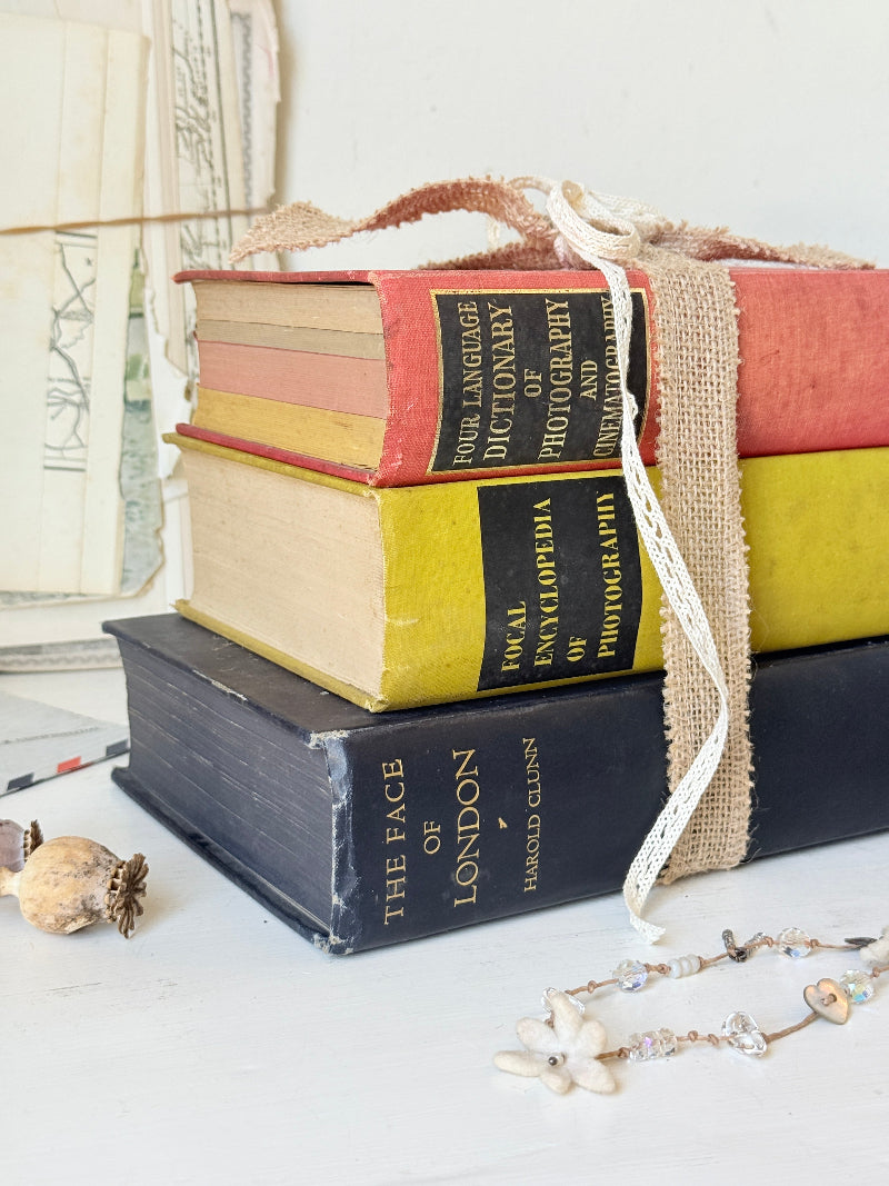 Vintage decorative book bundle in blue yellow and red with aged hardback covers tied with natural ribbon for bookshelf styling