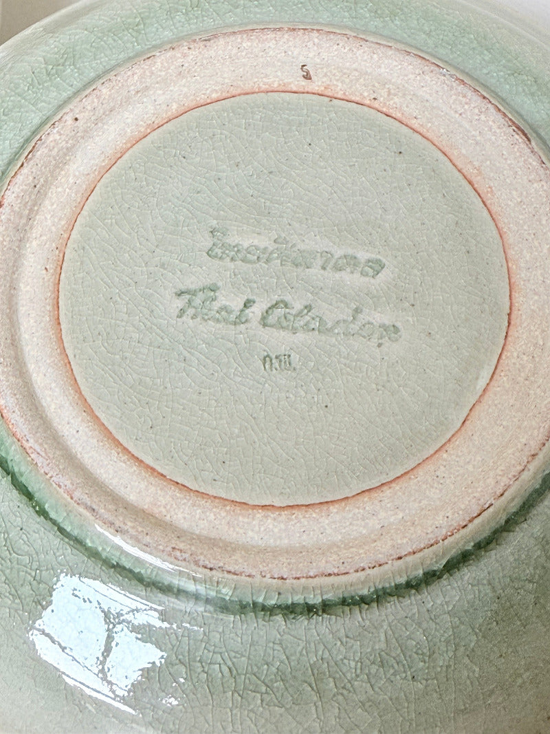 Set of four Thai stoneware plates with soft green celadon glaze on white surface