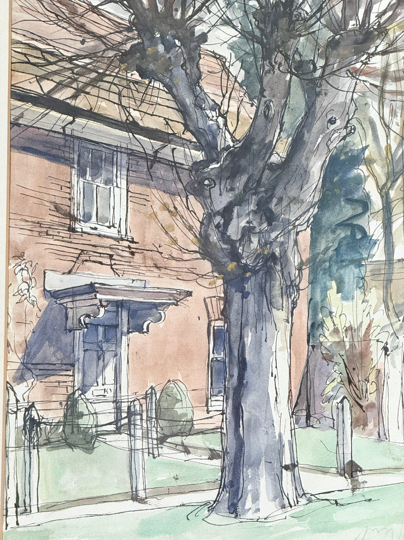 Framed vintage watercolour painting of a large tree and brick house, photographed on a white surface.
