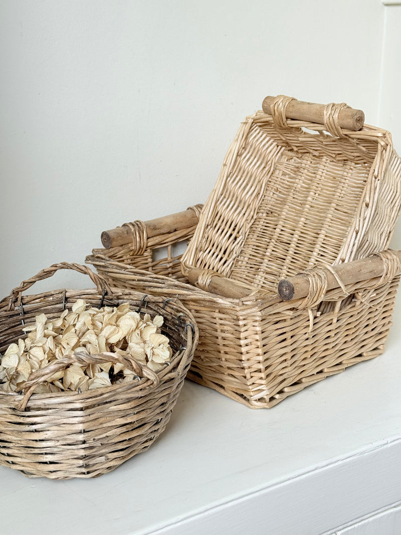 Set of three vintage woven willow baskets in natural tones photographed on a white surface