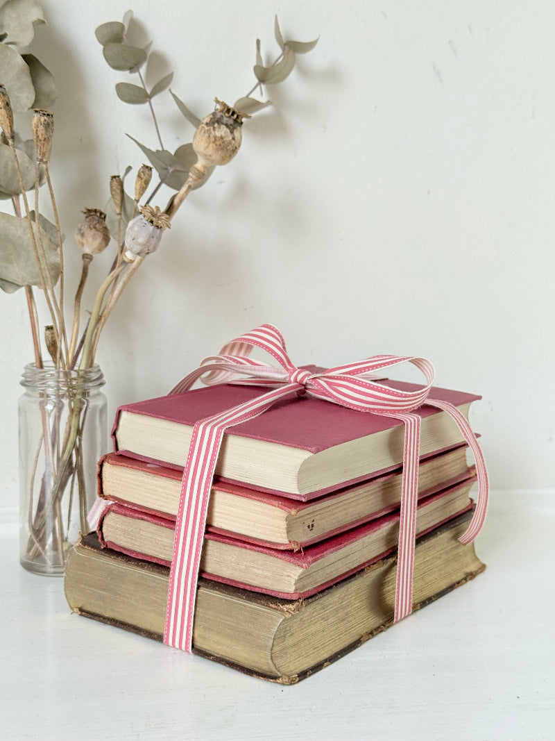 Vintage autumn colours decorative book bundle with pink ribbon, photographed on a white surface