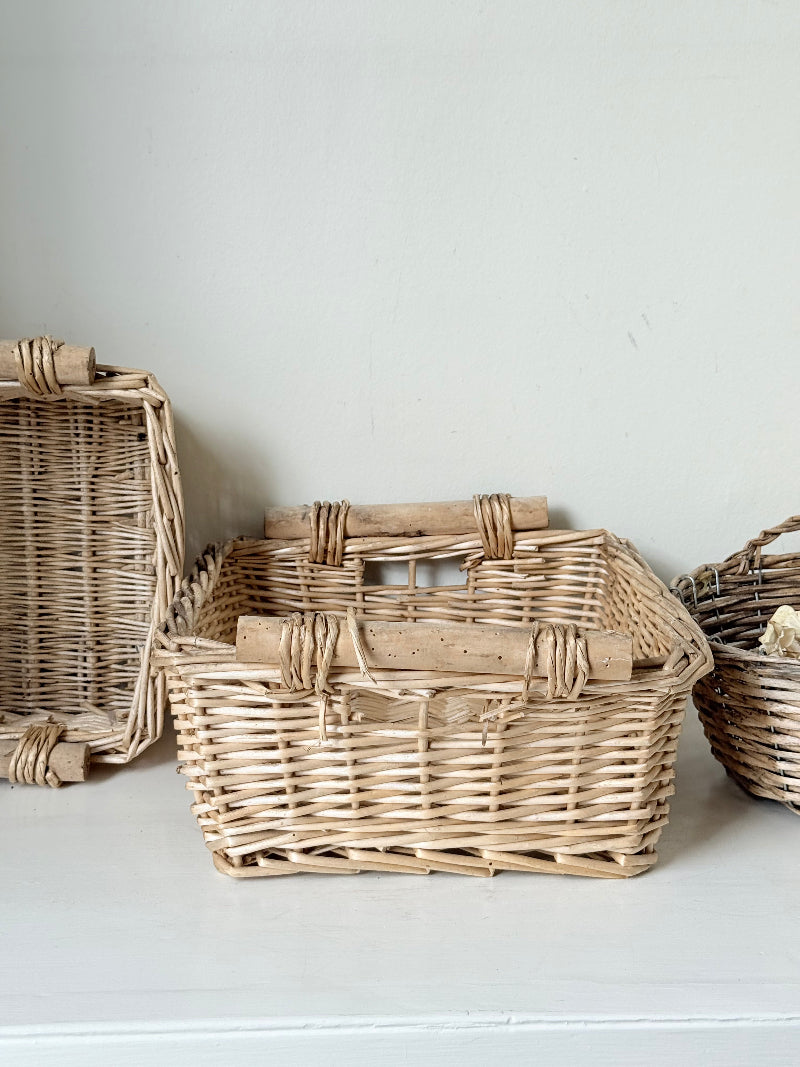 Set of three vintage woven willow baskets in natural tones photographed on a white surface