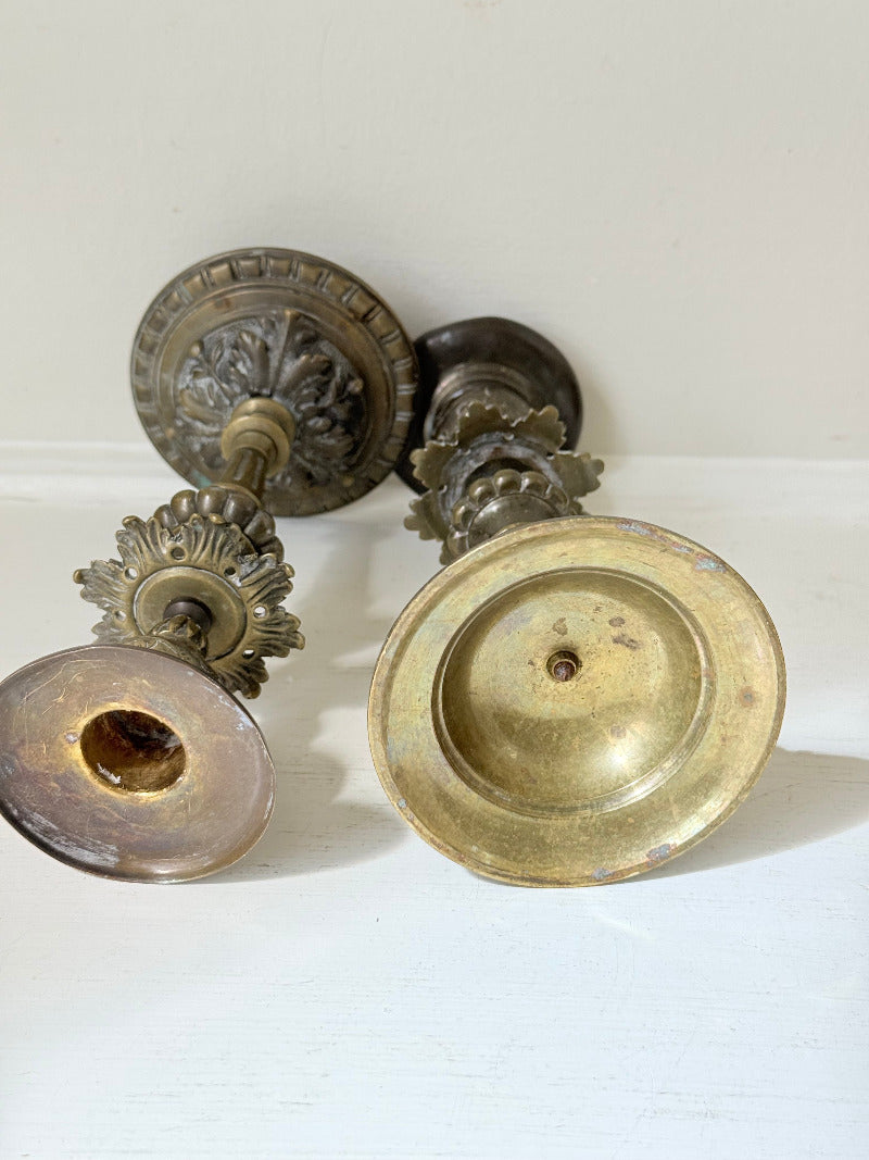 pair of antique brass candlesticks with turned detailing on white surface