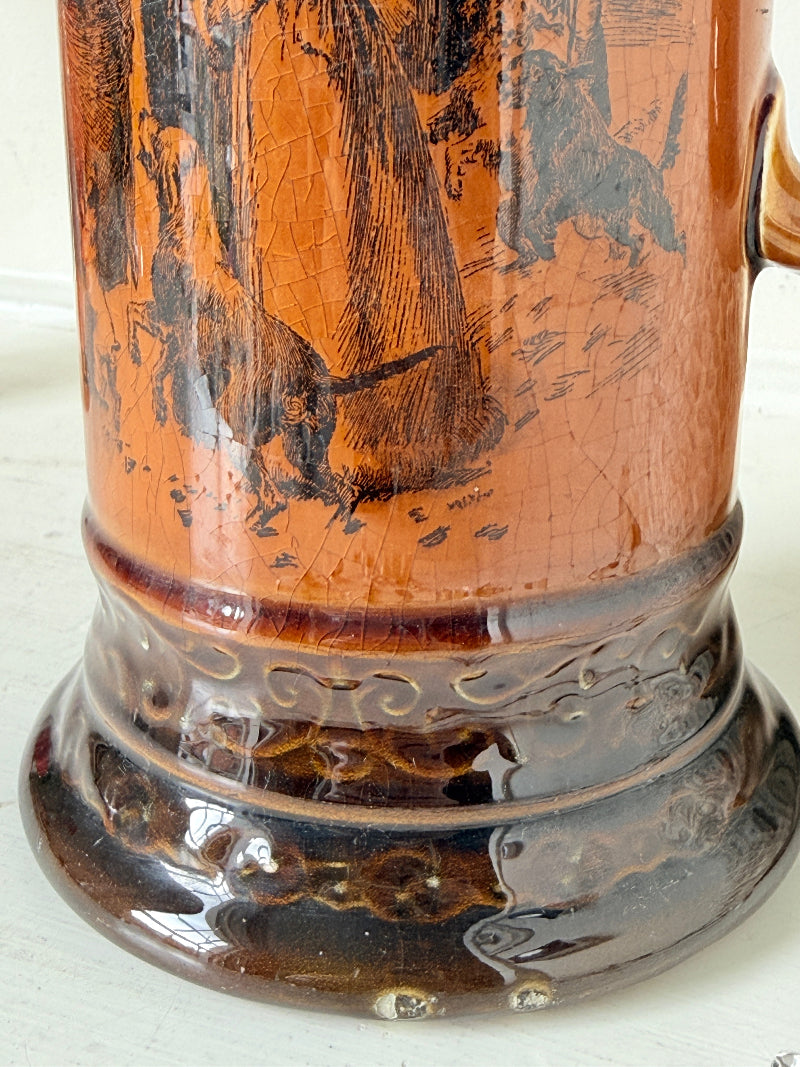 Antique Ridgways stoneware jug photographed on a white surface in amber treacle glaze with A Christmas Visitor black transfer scene and tall handle