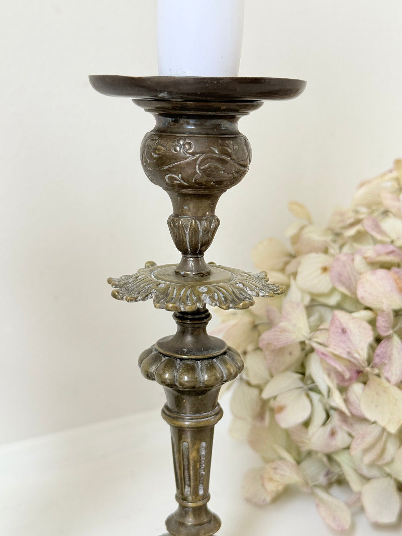 pair of antique brass candlesticks with turned detailing on white surface