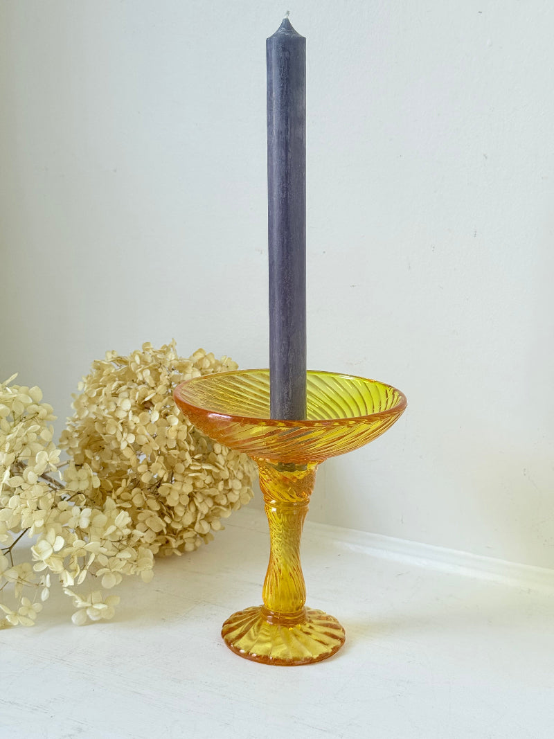 Amber pressed glass candle holder or compote with swirl design and pedestal base, photographed on a white background