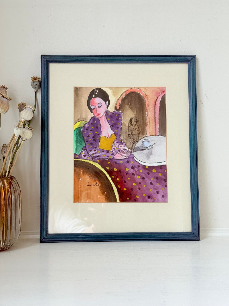 Original watercolour portrait of Pamela in blue frame, vibrant interior scene, photographed on white surface