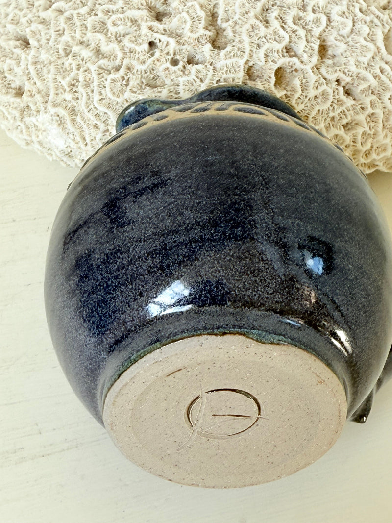 Studio pottery milk jug with deep blue glaze and cream geometric band, photographed on a white surface