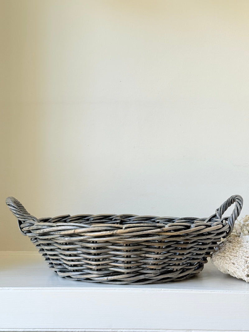Large vintage woven basket with handles, photographed on a white surface
