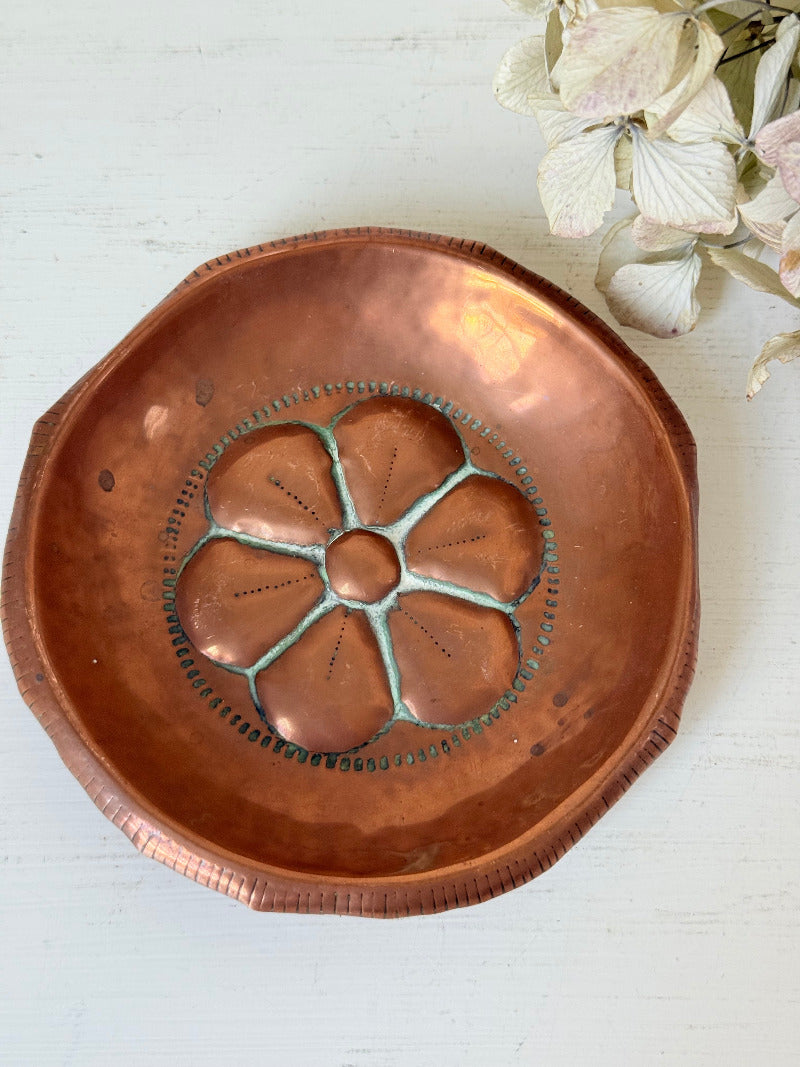 small vintage copper dish with cut-out floral centre photographed on white surface