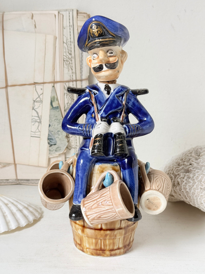 Vintage figural ceramic decanter set with captain, navy blue uniform, barrel base and 6 matching barrel shot cups