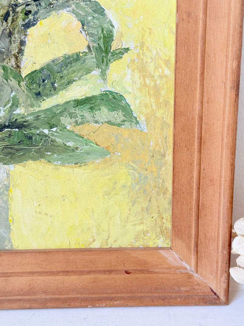 Vintage oil painting of cornflowers in a vase with yellow background in wooden frame photographed on a white surface