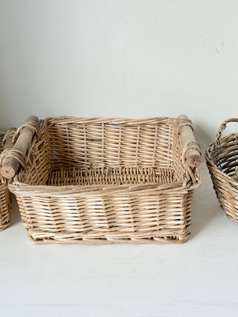 Set of three vintage woven willow baskets in natural tones photographed on a white surface
