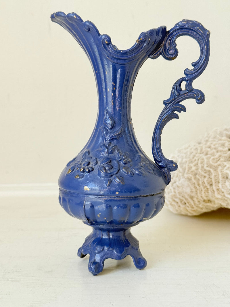 Blue vintage metal jug with ornate Rococo handle and relief decoration, shown on white background
