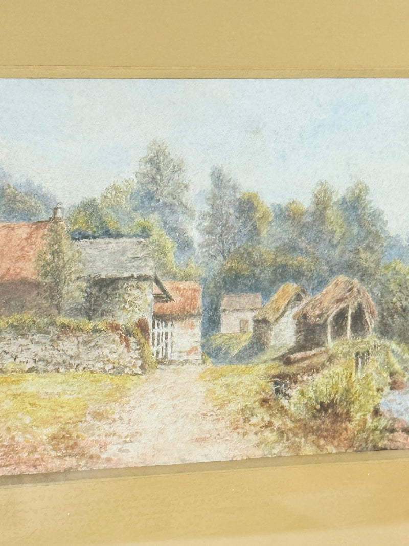 Framed vintage watercolour of countryside farm buildings with red roofs in gold frame photographed on a white surface
